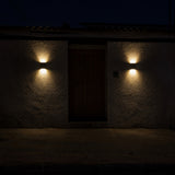 La entrada de una casa de noche con un aplique encendido a cada lado