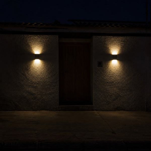 La entrada de una casa de noche con un aplique encendido a cada lado