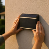 Manos pegando el aplique al muro, al atardecer