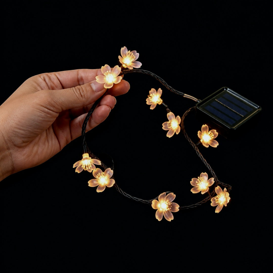 Una mano sosteniendo un tramo de la guirnalda con dos flores encendidas